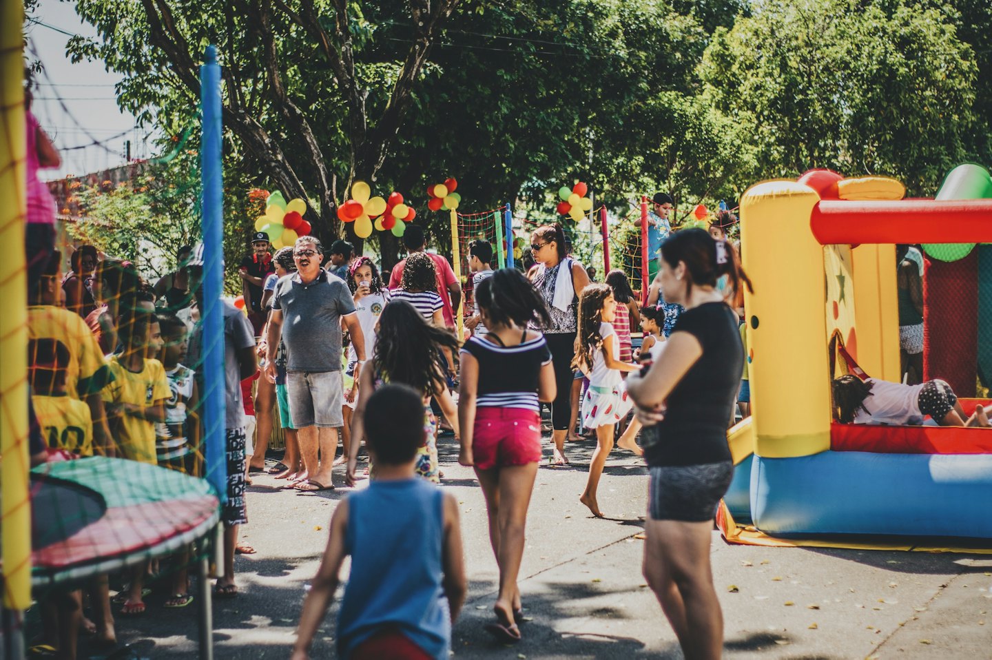 Adults and children play at an outdoor community event with bouncy castles.