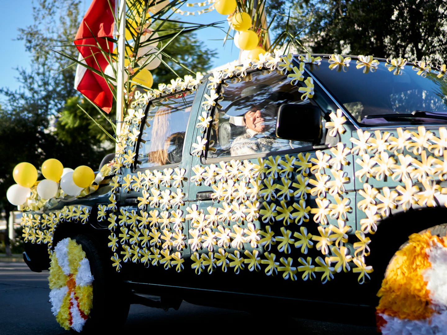 Decorated pickup truck with balloons driving in a parade.
